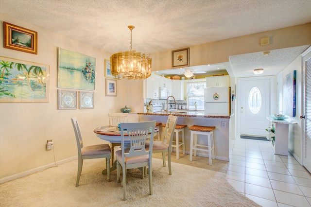 dining space featuring a textured ceiling, light tile patterned flooring, a chandelier, and sink