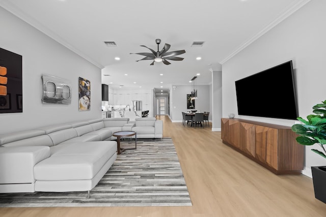 living room with ceiling fan, light wood-type flooring, and crown molding