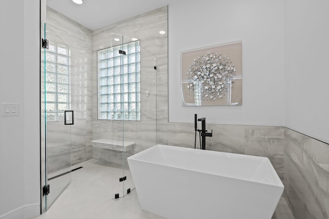 bathroom with separate shower and tub and tile walls