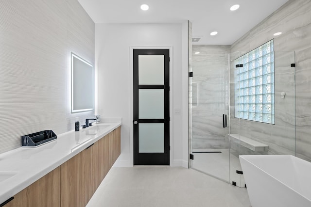 bathroom with tile patterned floors, vanity, independent shower and bath, and tile walls