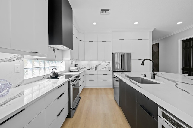 kitchen featuring sink, light hardwood / wood-style flooring, ornamental molding, appliances with stainless steel finishes, and white cabinetry