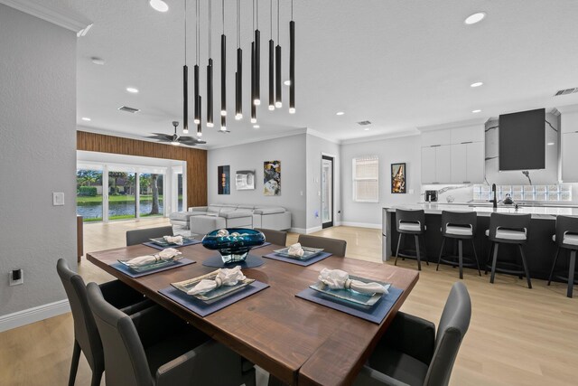 dining area featuring ceiling fan, light wood-type flooring, and crown molding