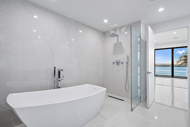 bathroom featuring shower with separate bathtub, a water view, and tile walls