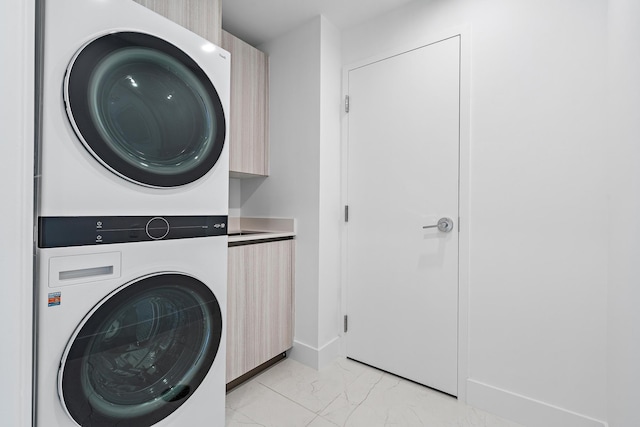 clothes washing area featuring cabinets and stacked washing maching and dryer