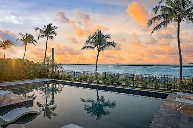 pool at dusk with a water view and a patio