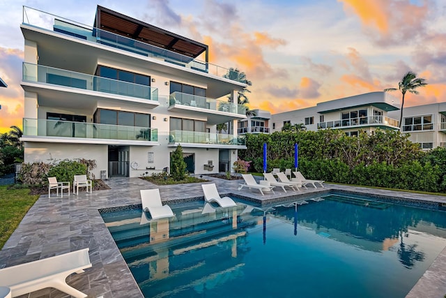 pool at dusk featuring a patio