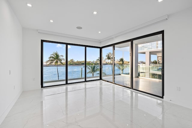 empty room with baseboards, a water view, ornamental molding, recessed lighting, and marble finish floor