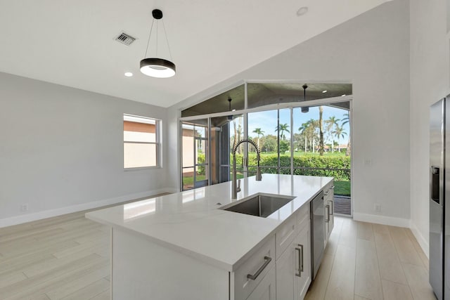 kitchen with light stone countertops, sink, a center island with sink, white cabinetry, and hanging light fixtures