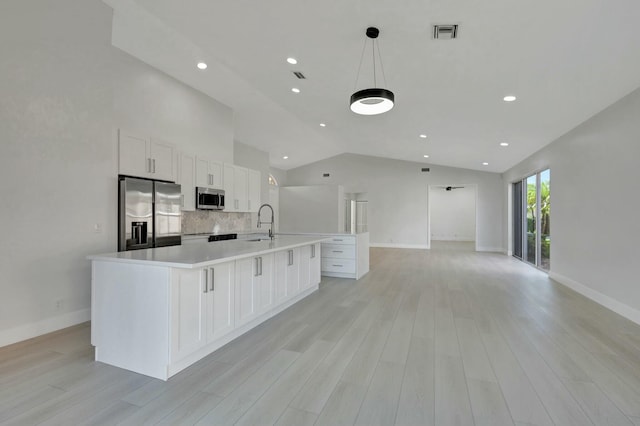 kitchen with lofted ceiling, a spacious island, sink, white cabinetry, and stainless steel appliances