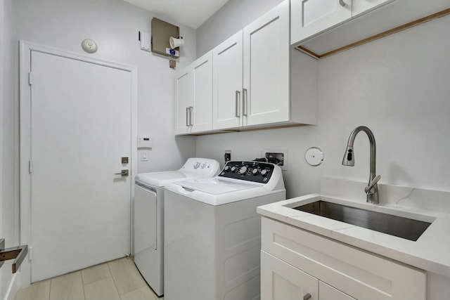 laundry room with washer and dryer, cabinets, and sink