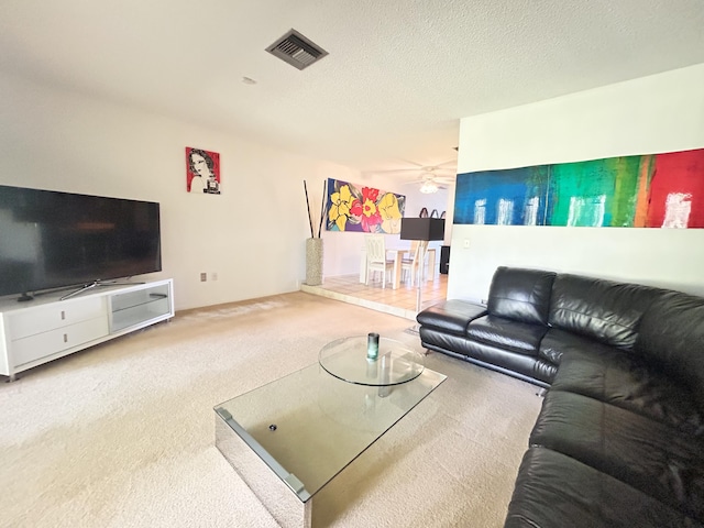 carpeted living room featuring ceiling fan and a textured ceiling