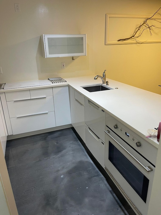 kitchen with wall oven, white cabinetry, and sink