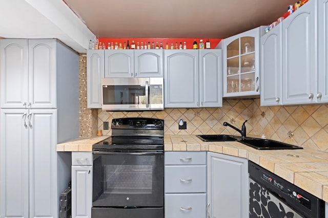 kitchen featuring tasteful backsplash, white cabinetry, tile counters, and black appliances