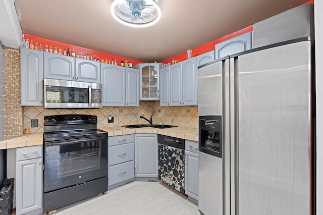 kitchen featuring tasteful backsplash, tile counters, sink, and black appliances