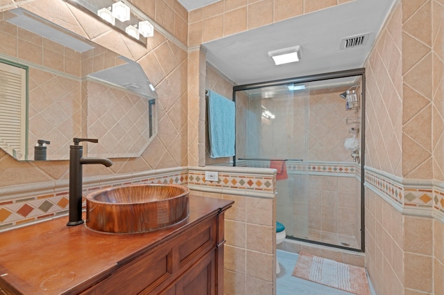 bathroom with tile walls, vanity, an enclosed shower, and toilet