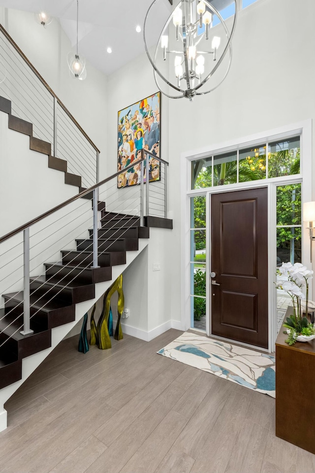 entrance foyer featuring light hardwood / wood-style floors, a chandelier, and a high ceiling