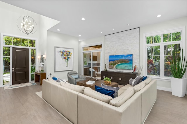 living room with a healthy amount of sunlight, light hardwood / wood-style flooring, and a notable chandelier