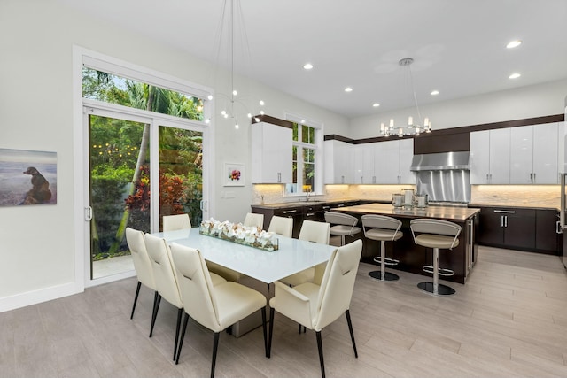 dining area with sink, a notable chandelier, and light hardwood / wood-style floors