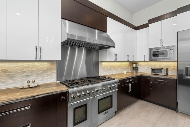 kitchen featuring stainless steel appliances, white cabinetry, dark brown cabinets, and range hood