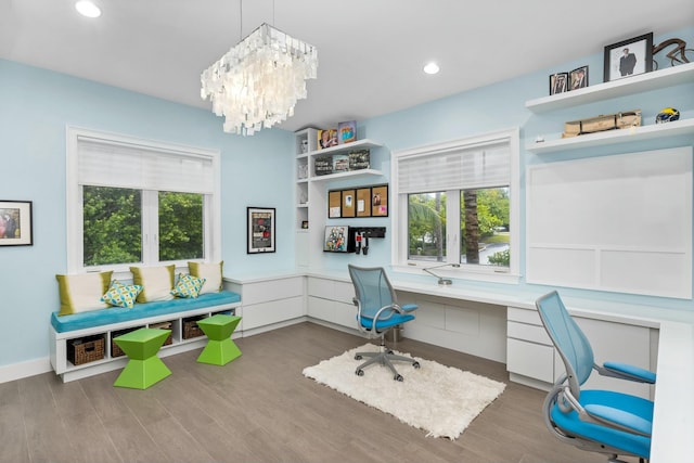 office area with a notable chandelier, built in desk, and wood-type flooring