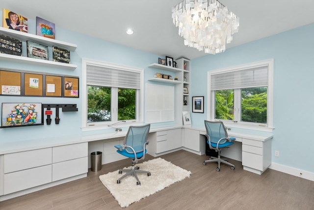 home office with plenty of natural light, built in desk, light hardwood / wood-style floors, and a notable chandelier