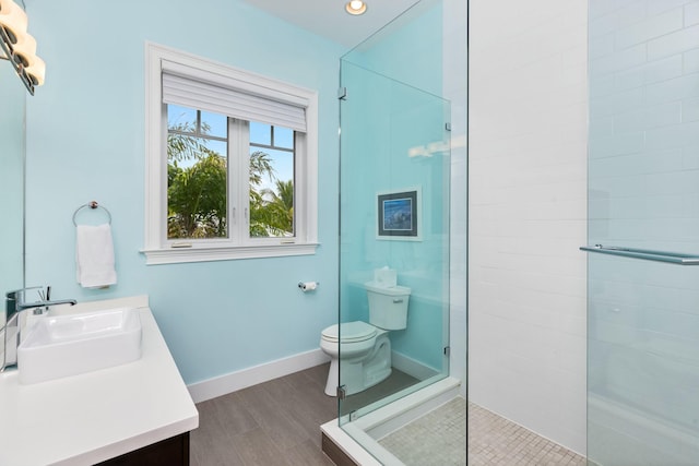 bathroom featuring vanity, hardwood / wood-style flooring, toilet, and a tile shower