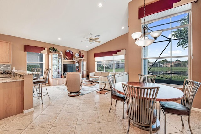 dining space featuring ceiling fan with notable chandelier, light tile patterned flooring, lofted ceiling, and sink