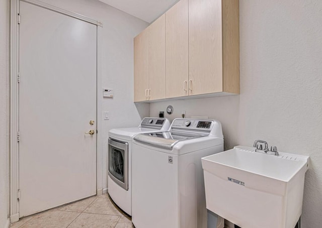 washroom featuring separate washer and dryer, sink, light tile patterned flooring, and cabinets