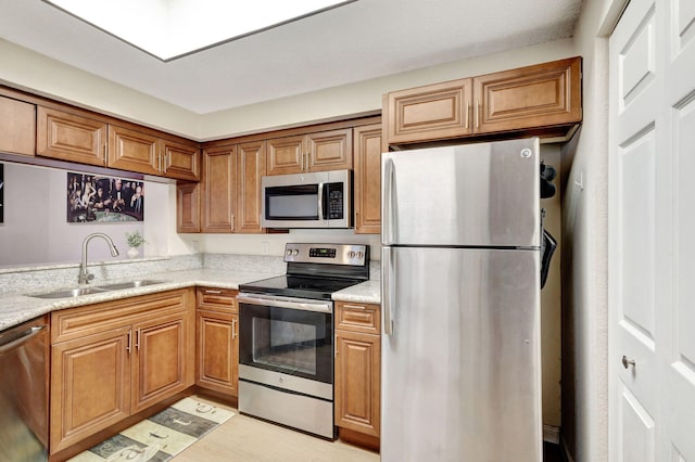 kitchen with light stone countertops, appliances with stainless steel finishes, and sink