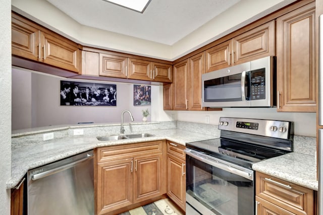 kitchen with light stone countertops, sink, and appliances with stainless steel finishes