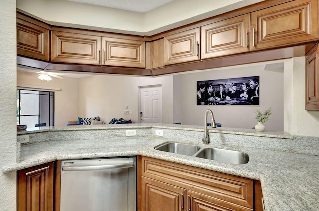 kitchen with light stone counters, stainless steel dishwasher, and sink