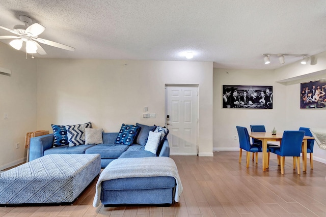 living room with ceiling fan, wood-type flooring, and a textured ceiling