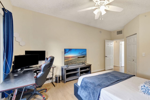 bedroom with ceiling fan, light hardwood / wood-style flooring, and a textured ceiling