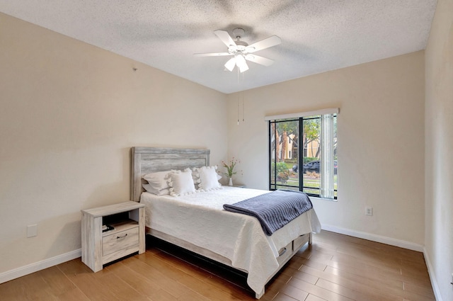 bedroom featuring ceiling fan, hardwood / wood-style floors, and a textured ceiling