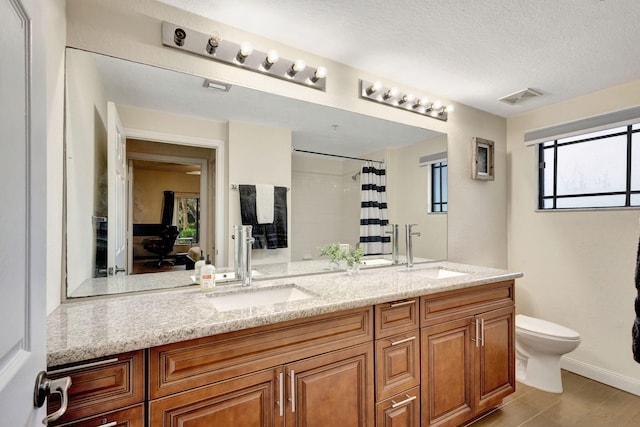 bathroom featuring walk in shower, vanity, a textured ceiling, and toilet