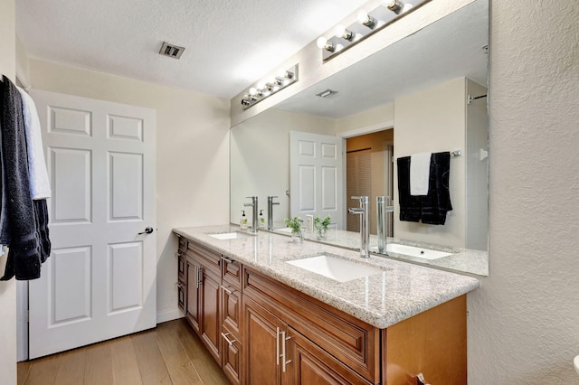 bathroom featuring hardwood / wood-style flooring, vanity, and a textured ceiling