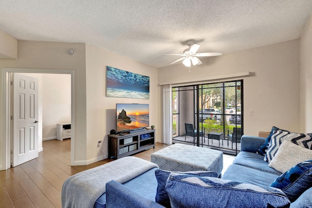 living room featuring ceiling fan, a textured ceiling, and light hardwood / wood-style flooring