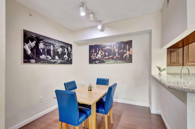 dining area with dark hardwood / wood-style flooring and rail lighting