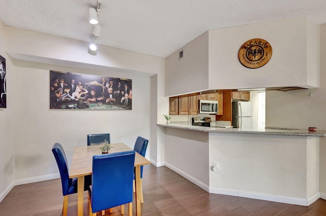 dining space featuring rail lighting, dark hardwood / wood-style flooring, and a textured ceiling