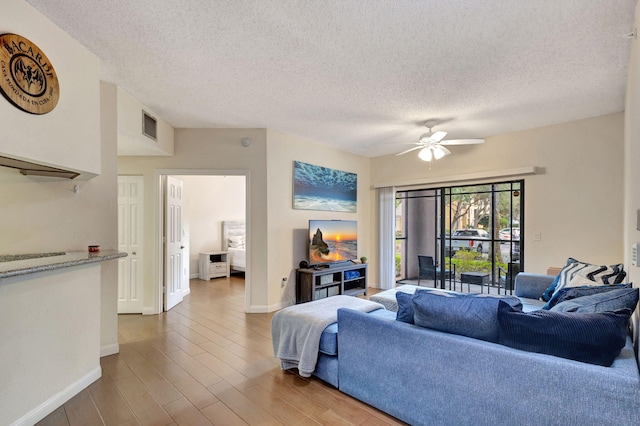 living room featuring hardwood / wood-style floors, ceiling fan, and a textured ceiling