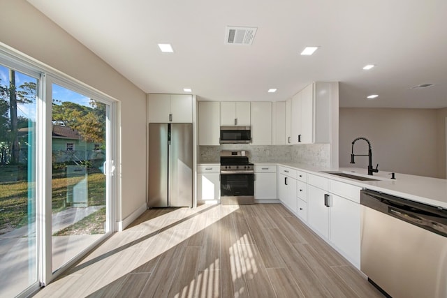 kitchen featuring white cabinets, appliances with stainless steel finishes, backsplash, and sink