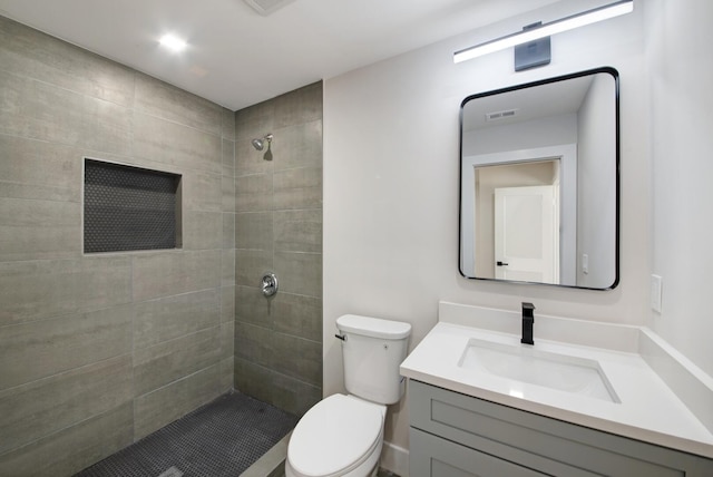 bathroom with tiled shower, vanity, and toilet