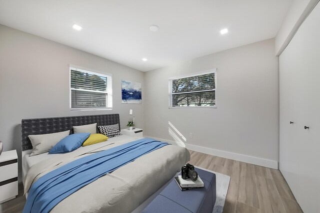 bedroom featuring multiple windows, a closet, and light hardwood / wood-style flooring