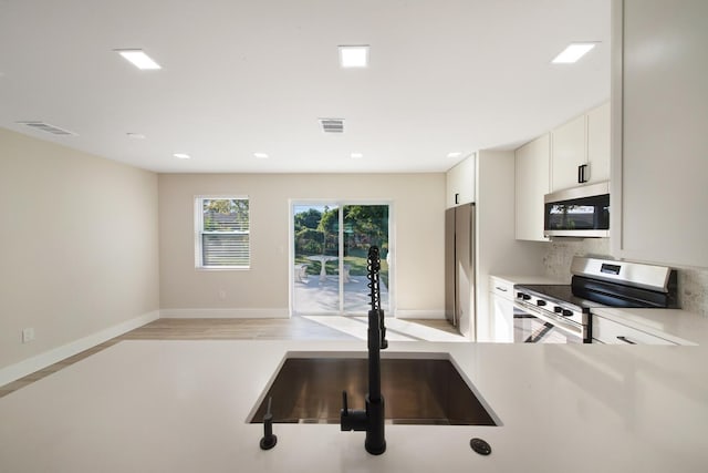 kitchen featuring white cabinets, appliances with stainless steel finishes, decorative backsplash, and sink