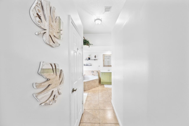 hall with light tile patterned flooring and a textured ceiling