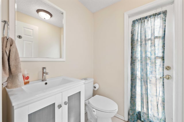 bathroom with toilet, vanity, and a textured ceiling