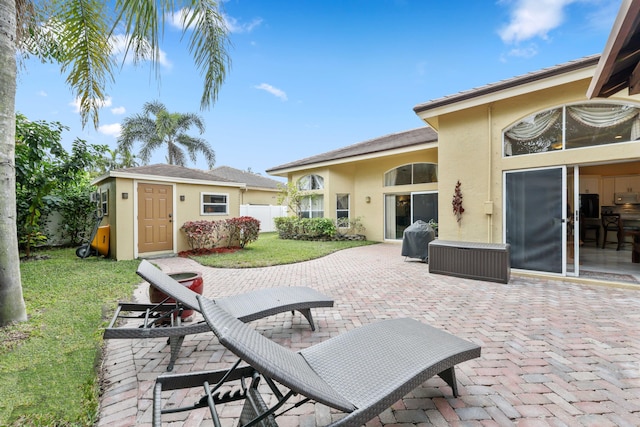 back of house featuring a patio, an outdoor structure, and a lawn