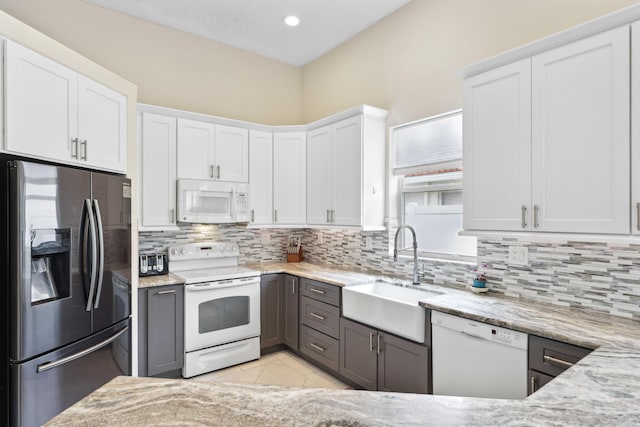 kitchen featuring sink, white cabinetry, white appliances, light tile patterned floors, and light stone countertops