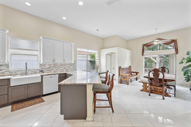 kitchen featuring decorative light fixtures, decorative backsplash, white dishwasher, and sink