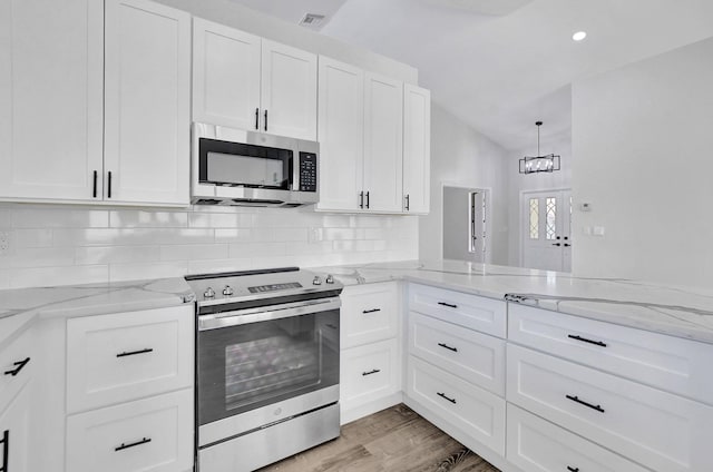 kitchen with decorative backsplash, white cabinets, and stainless steel appliances